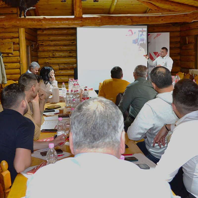 Participanți la un curs UnivAgx urmărind o prezentare într-o sală cu pereți din lemn.